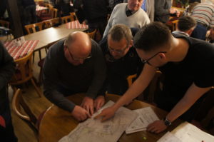 Mehrere Personen über Planungskarten gebäugt, diskutierend
