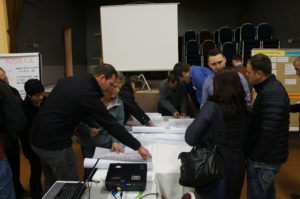 Mehrere Personen über Planungskarten gebäugt, diskutierend